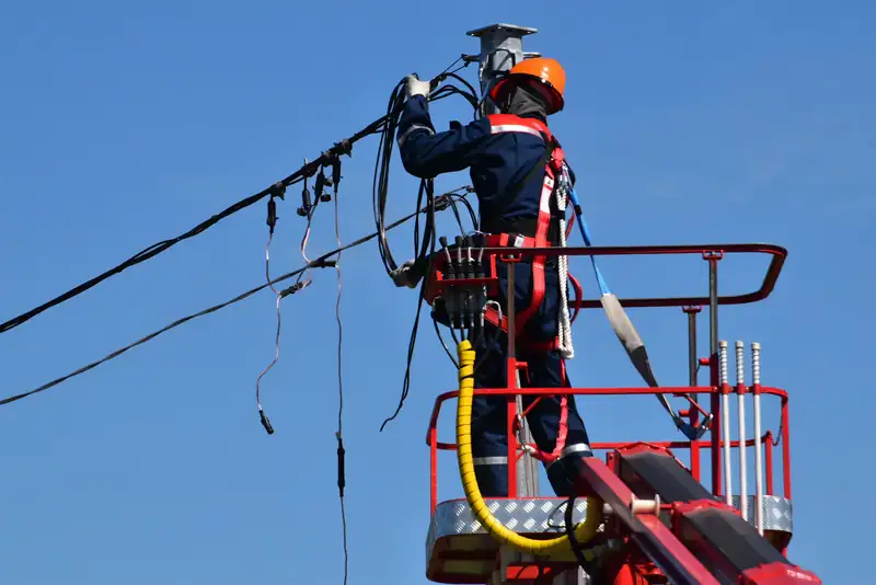 Electrician in hard hat and harness restoring power